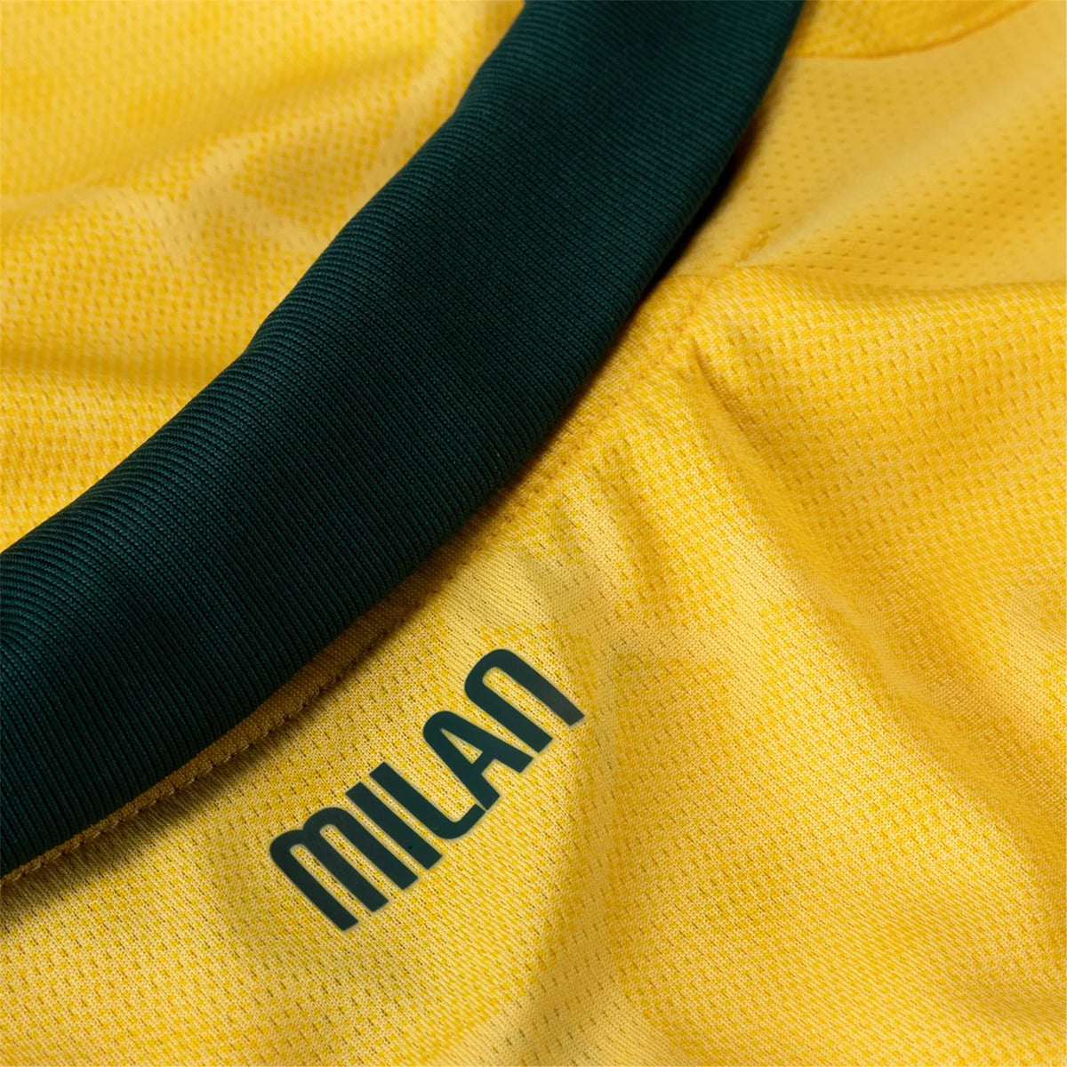 Close-up of a yellow fabric with a green stripe and 'Milan' branding.
