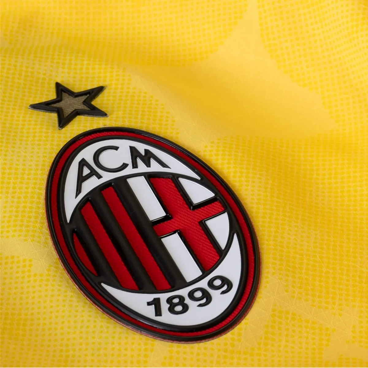 Close-up of a yellow sports jersey with a prominent logo featuring 'ACM 1899'.