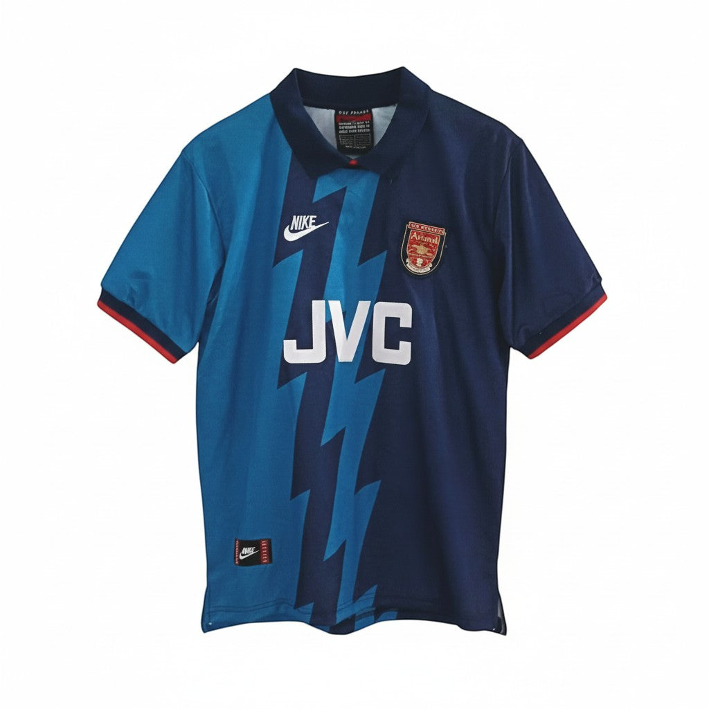 Hinchas Sportswear Store Arsenal 1994-95 retro away jersey. Navy blue with electric blue lightning pattern, JVC sponsor, Nike logo, and Arsenal crest.