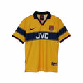 Hinchas Sportswear Store Arsenal 1997-99 retro away jersey. Yellow with navy chest band, JVC sponsor, red Nike swoosh, and Arsenal crest.