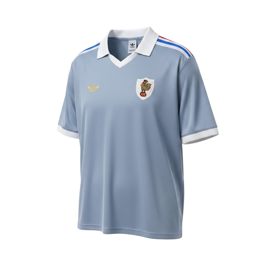 Camiseta retro de visitante de Francia 1982 de Hinchas Sportswear Store, de color azul grisáceo con cuello blanco, ribetes en las mangas y detalles de rayas en los hombros.