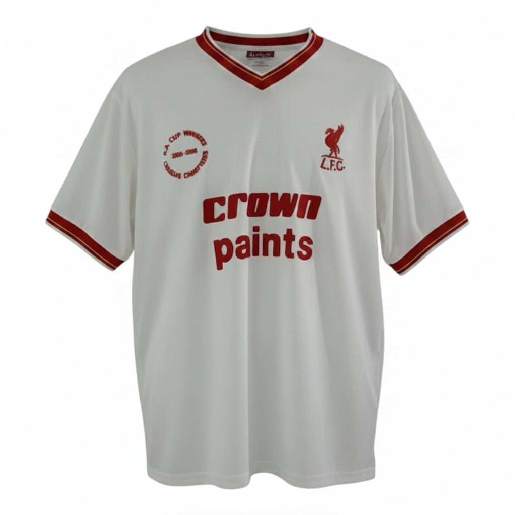 Hinchas Sportswear Store white Liverpool FC 1985/86 retro away shirt with red V-collar, sleeve cuffs, and 'Crown Paints' sponsor. Features LFC crest and commemorative patch.